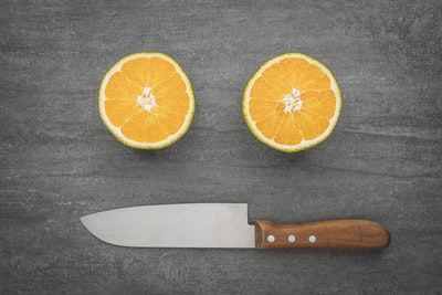 片橙色水果旁边黑色刀处理
